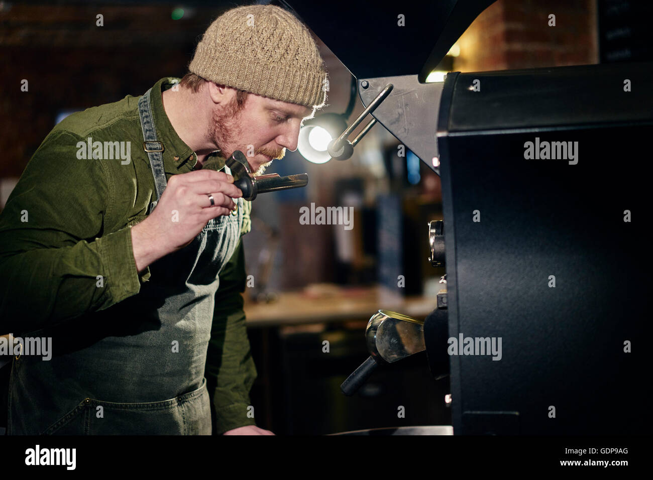 Male coffee shop owner at coffee machine smelling coffee Stock Photo