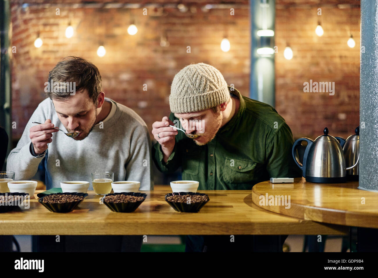 Coffee shop team slurping bowls of coffee and coffee beans at tasting