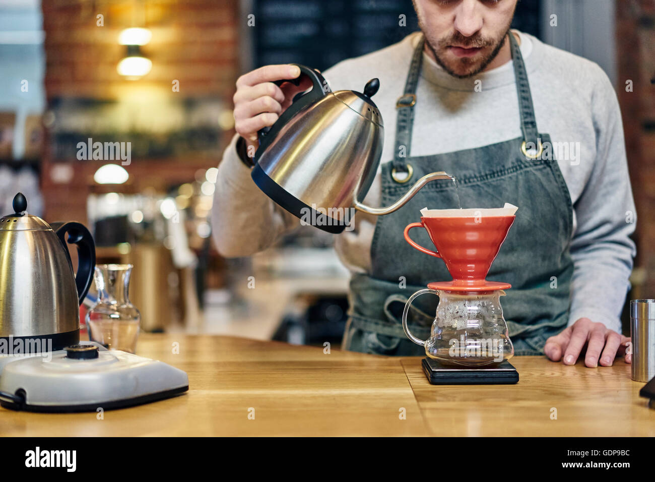 Barista pouring boiling water into coffee filter at coffee shop Stock Photo