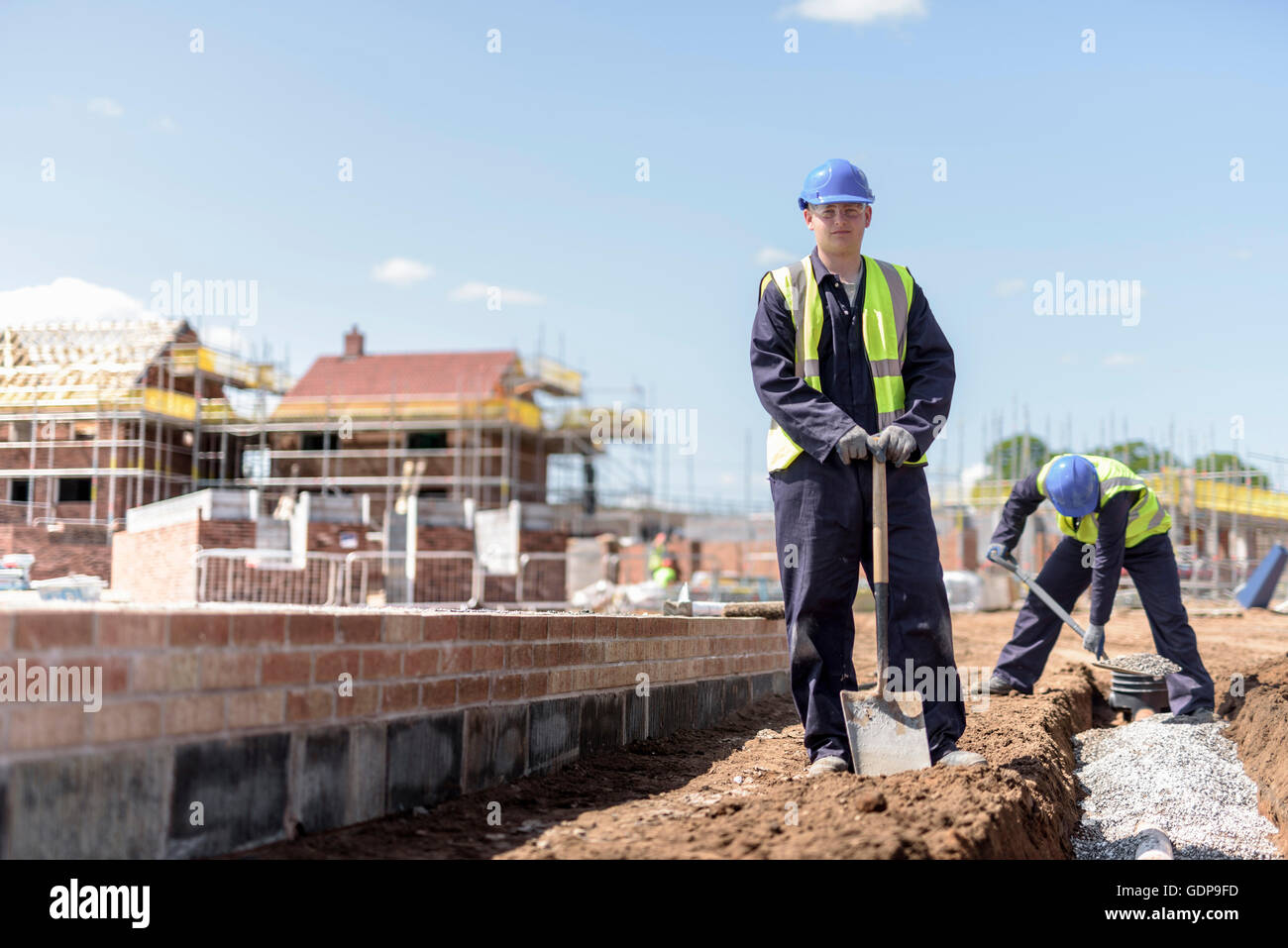 Portrait of apprentice builder laying pipework on housing building site Stock Photo