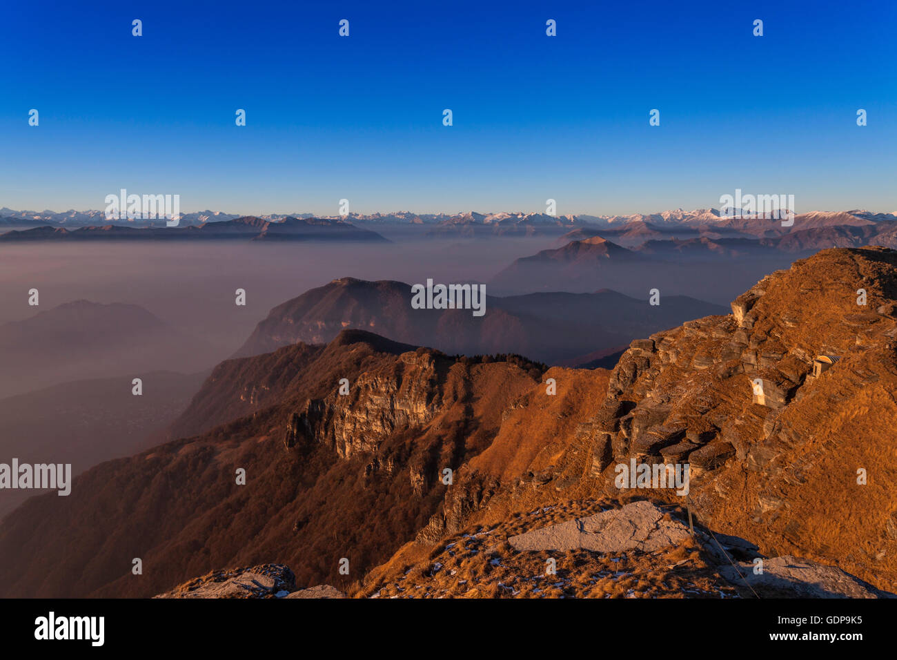 Elevated misty landscape with distant snow capped mountains, Monte Generoso,Ticino, Switzerland Stock Photo