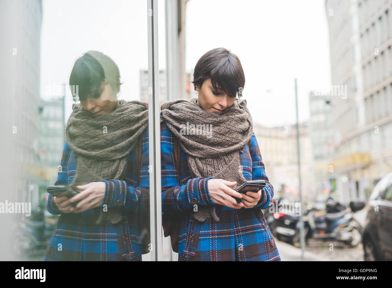 Young woman leaning against window, outdoors Stock Photo