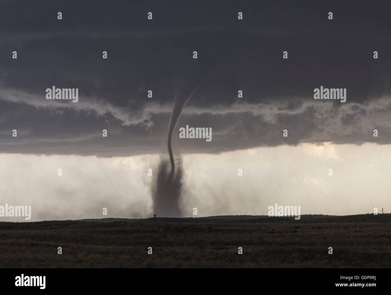 A fine tornado dances within a cloud of dust that moves in ringlets up the lower half of the tornado Stock Photo