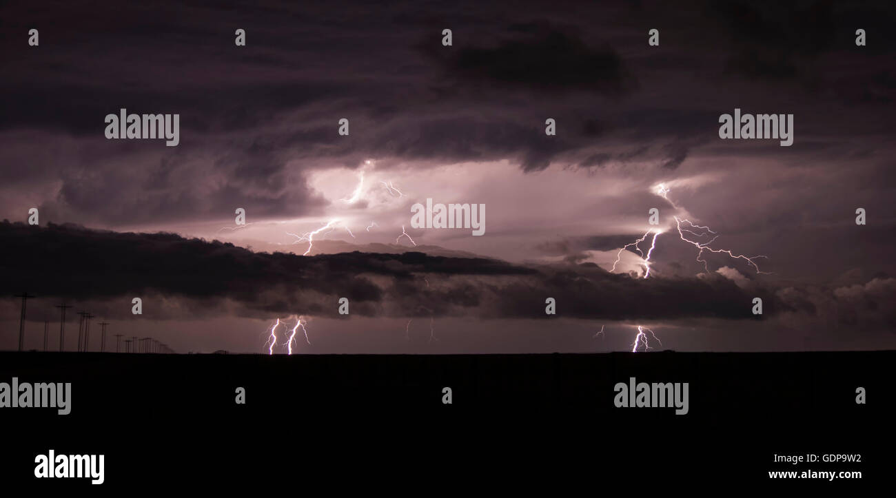 Two cloud-to-ground lightning bolts shoot through the low clouds of a supercell Stock Photo