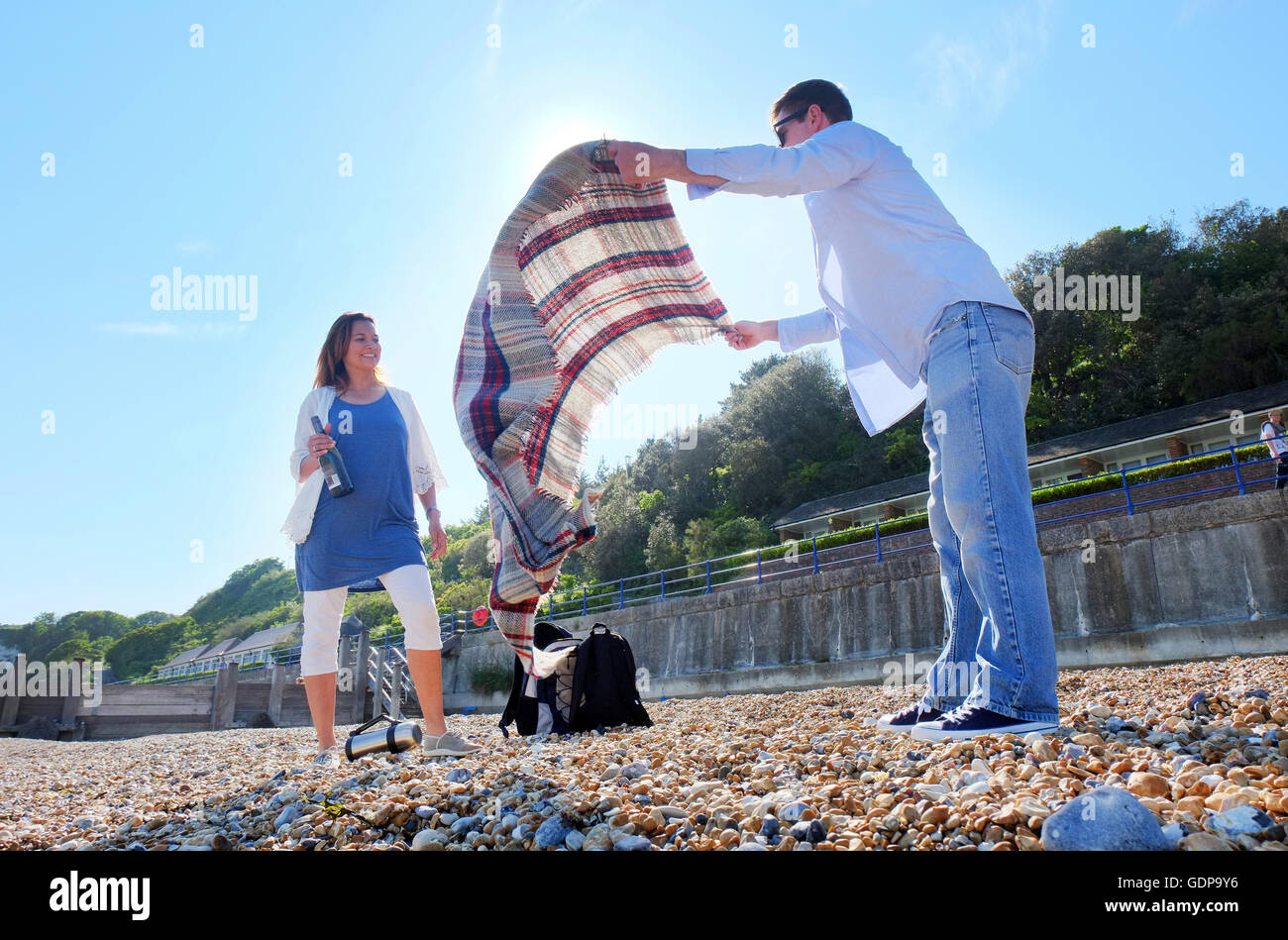 Couple placing picnic blanket on shingle beach Stock Photo