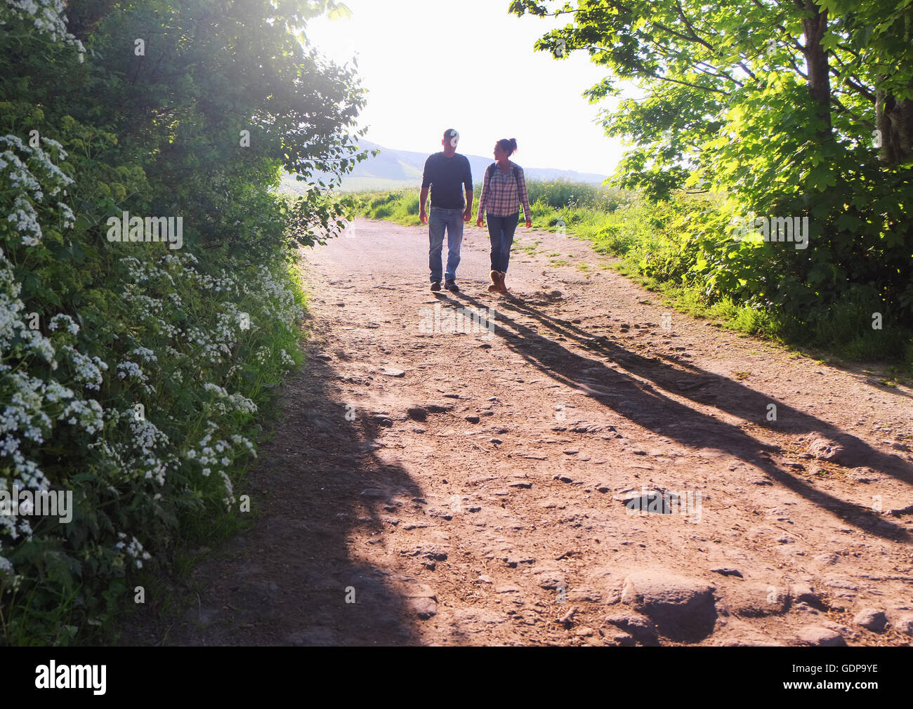 Rear view of couple walking on dirt track Stock Photo