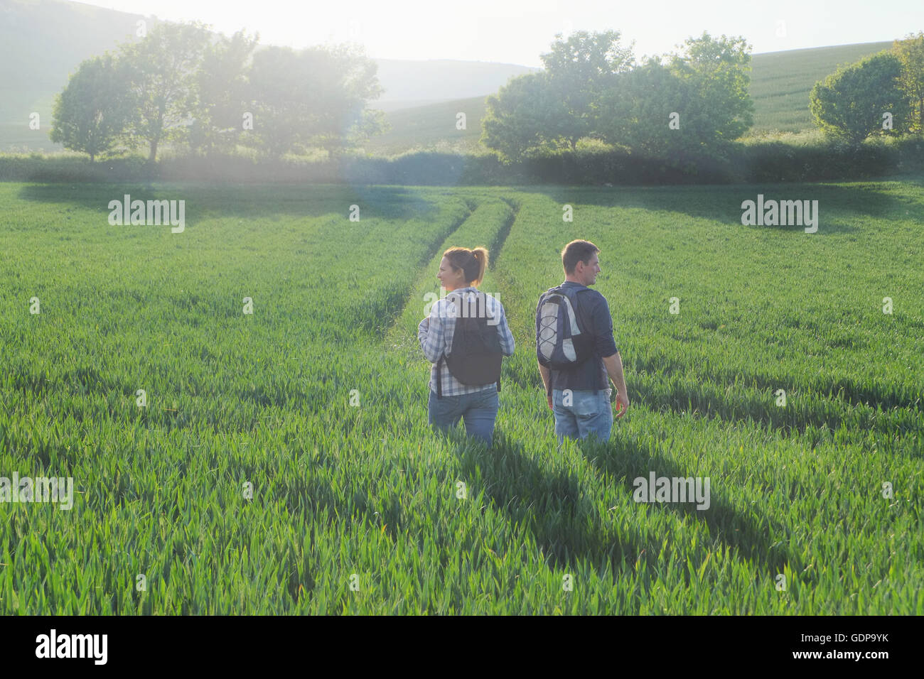 Rear view of couple hiking in field Stock Photo