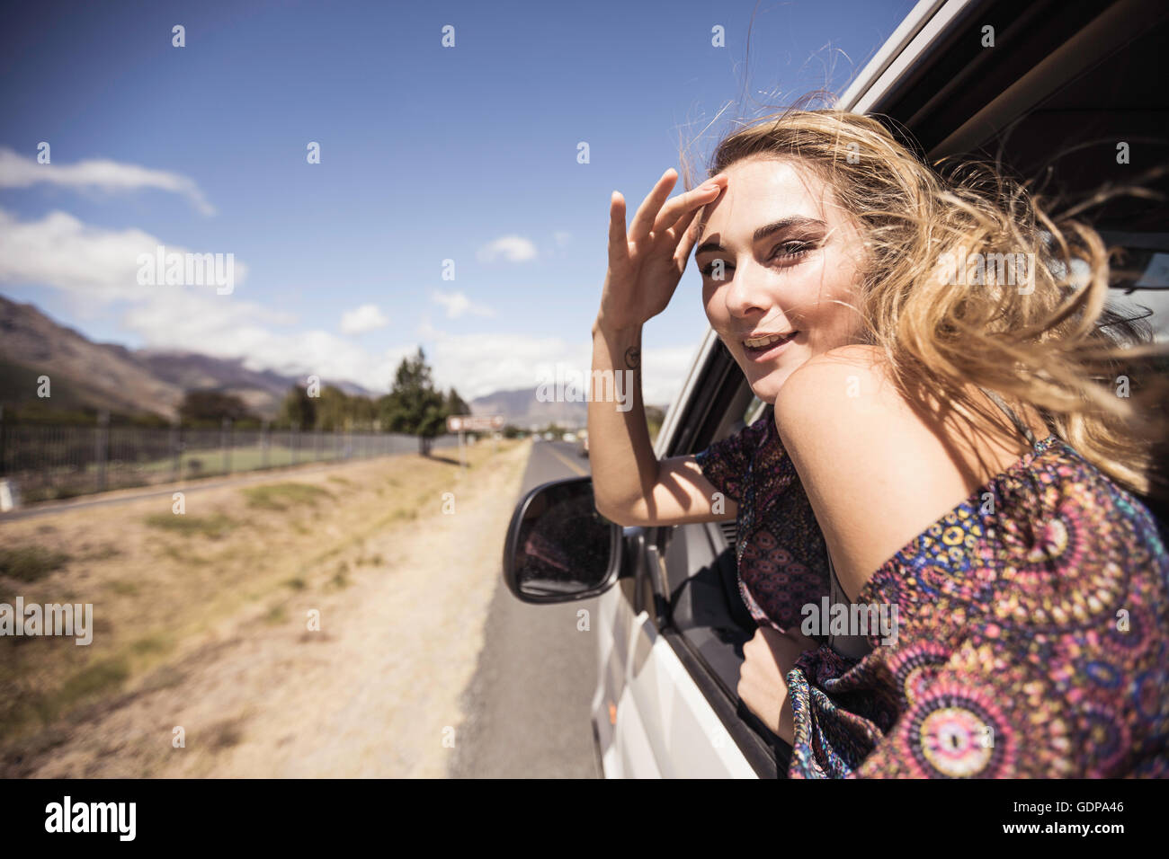 Woman looking out of car window shielding eyes Stock Photo