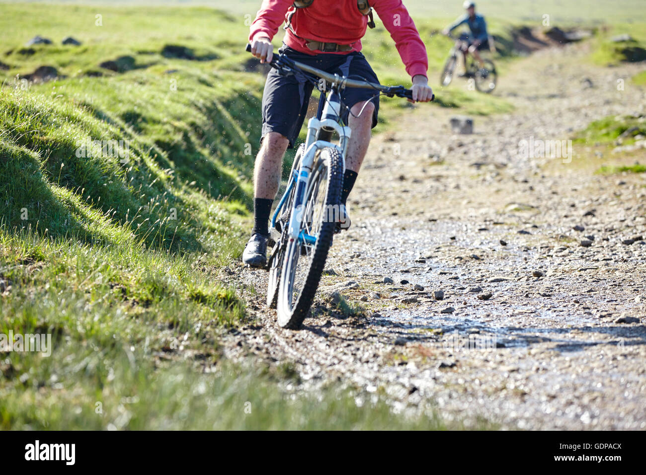 Cyclists cycling down dirt track Stock Photo