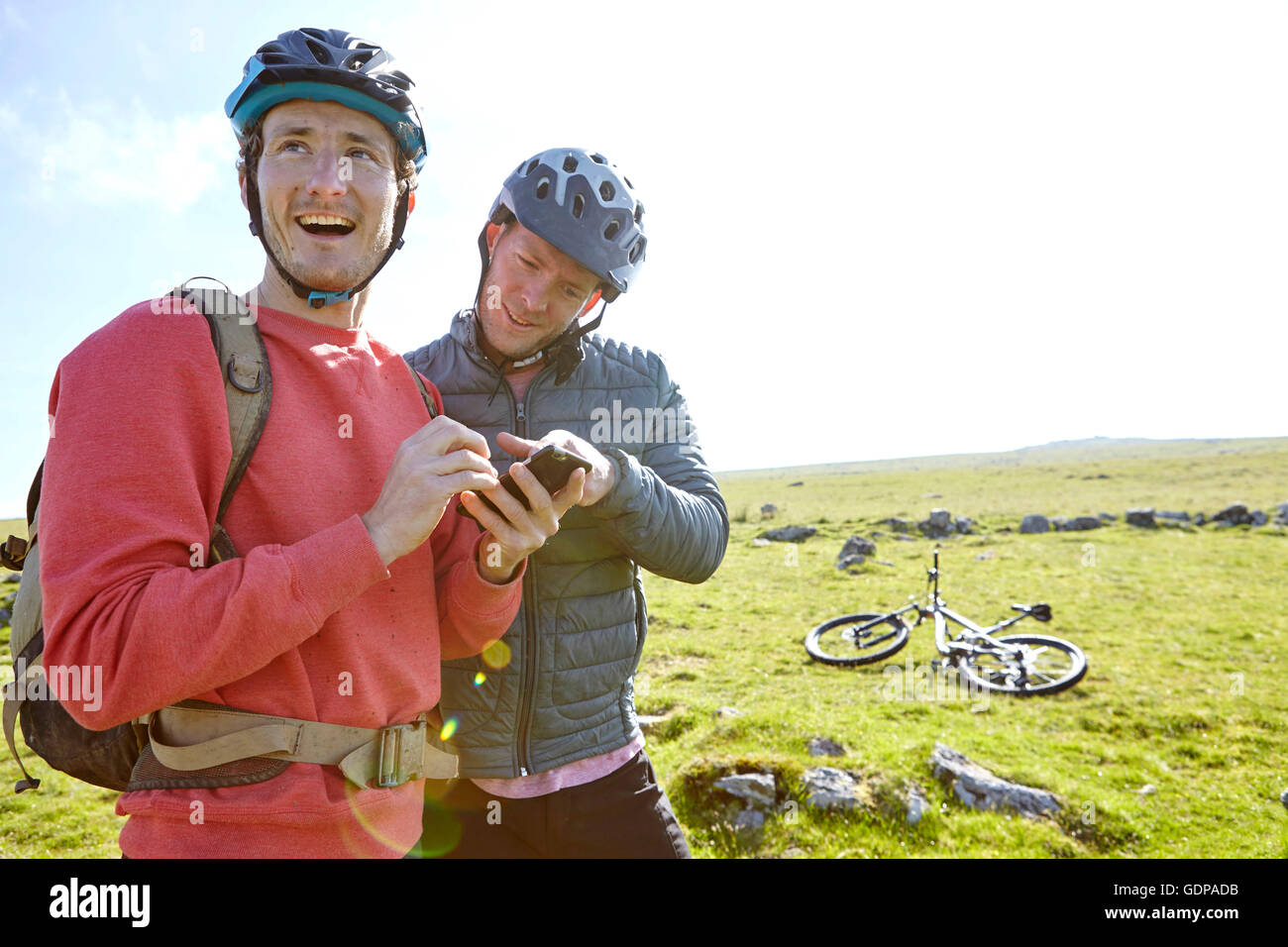 Cyclists on hillside looking at smartphone Stock Photo