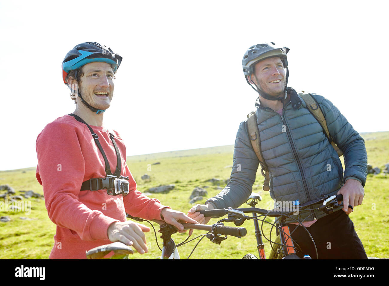 Cyclists on hillside holding bicycles looking away Stock Photo