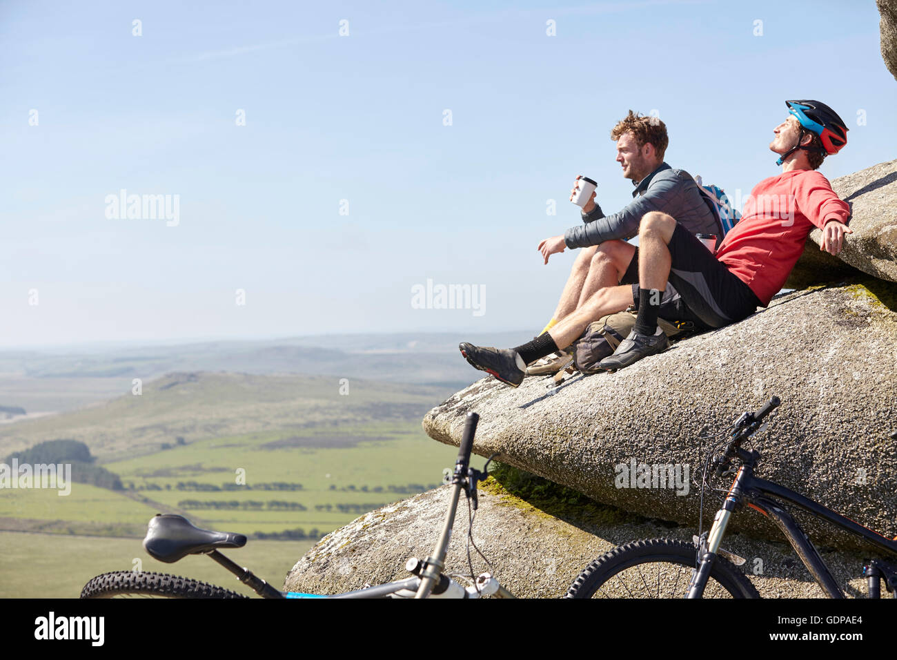 Cyclists resting on rocky outcrop Stock Photo