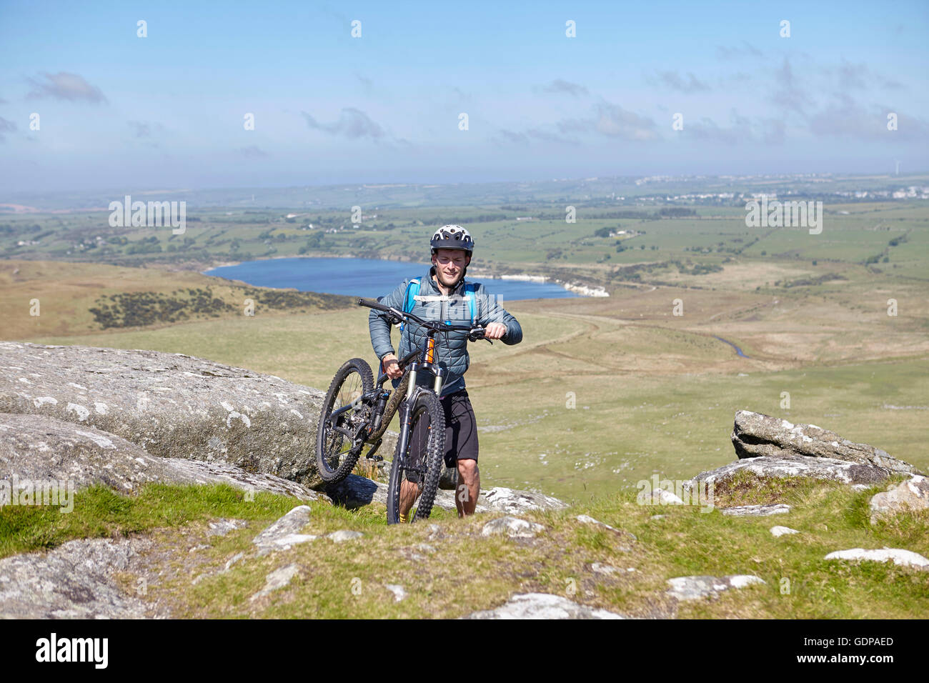 Cyclist carrying bicycle on rocky outcrop Stock Photo