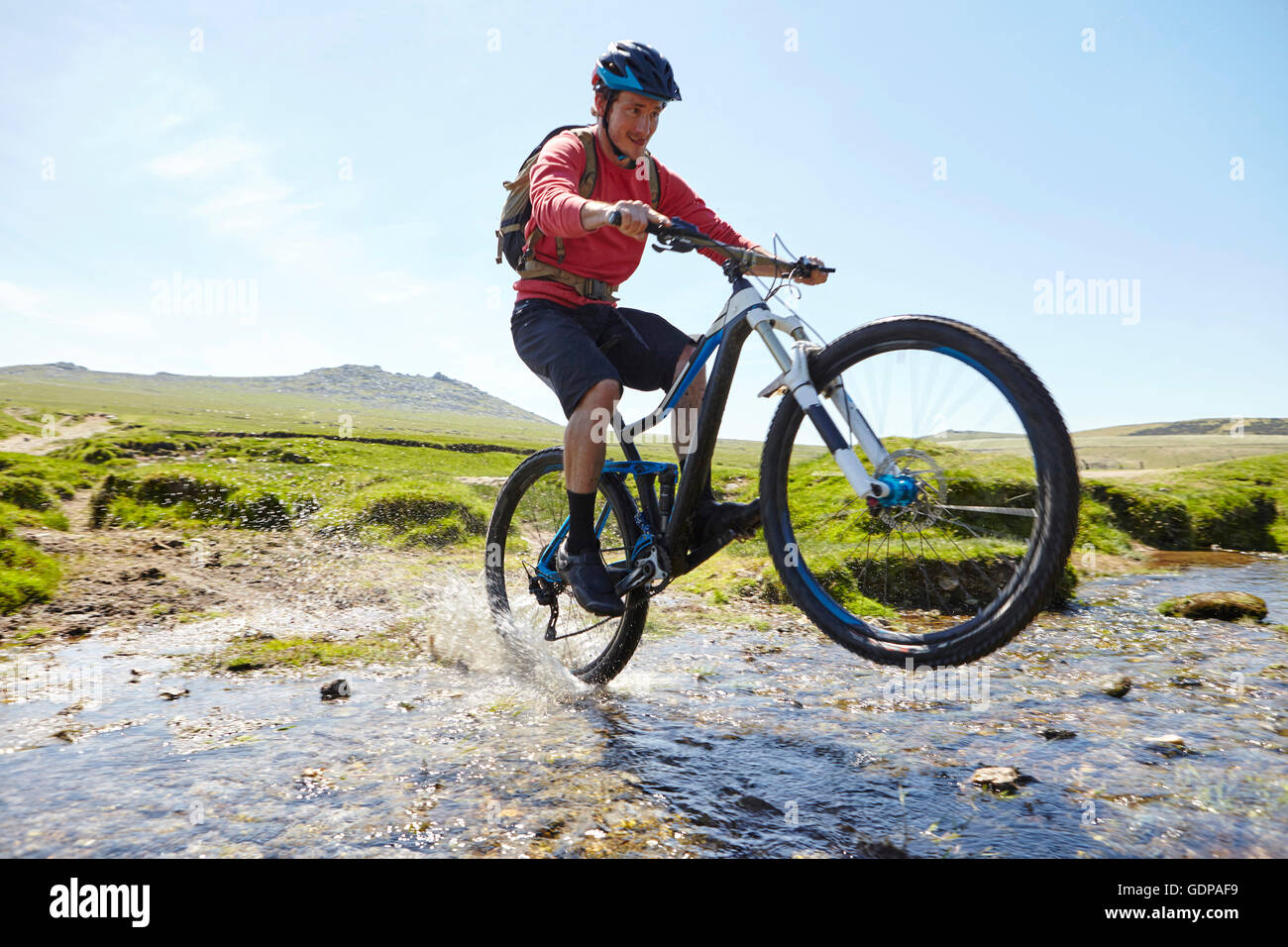 Cyclist doing wheelie through water Stock Photo Alamy