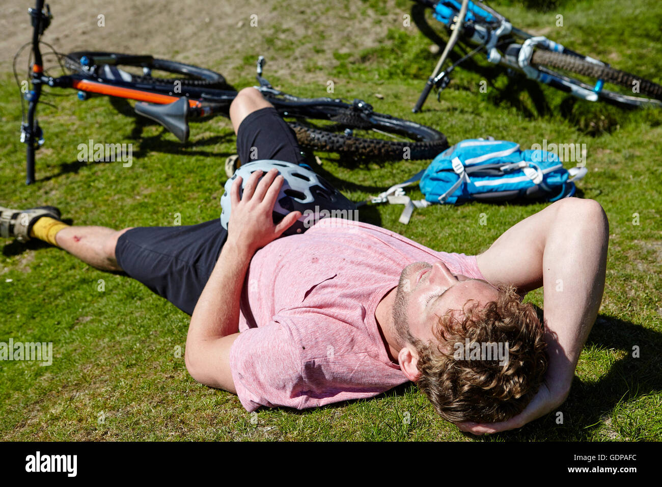 Cyclist lying down on grass by bicycle Stock Photo