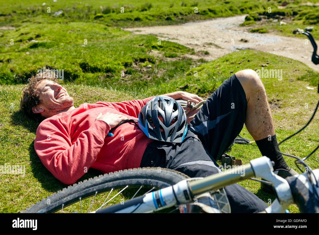 Cyclist lying down on grass by bicycle Stock Photo