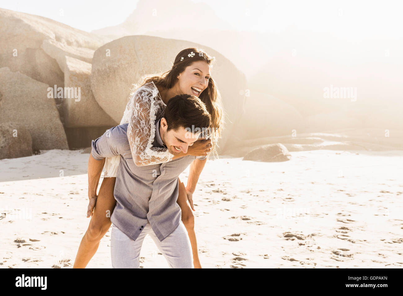 Man giving girlfriend a piggy back on sunlit beach, Cape Town, South
