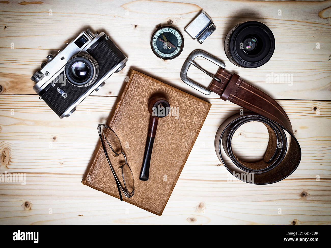 Still life with retro object. Book with compact old camera, compass, cigarette lighter, belt, glasses, pipe, dslr lens on wood t Stock Photo