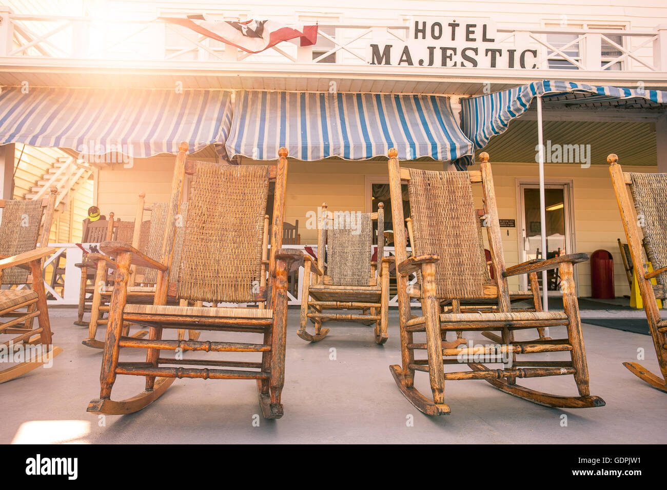 Old-fashioned wicker rocking chairs on traditional style resort hotel porch in late afternoon summer sun. Stock Photo