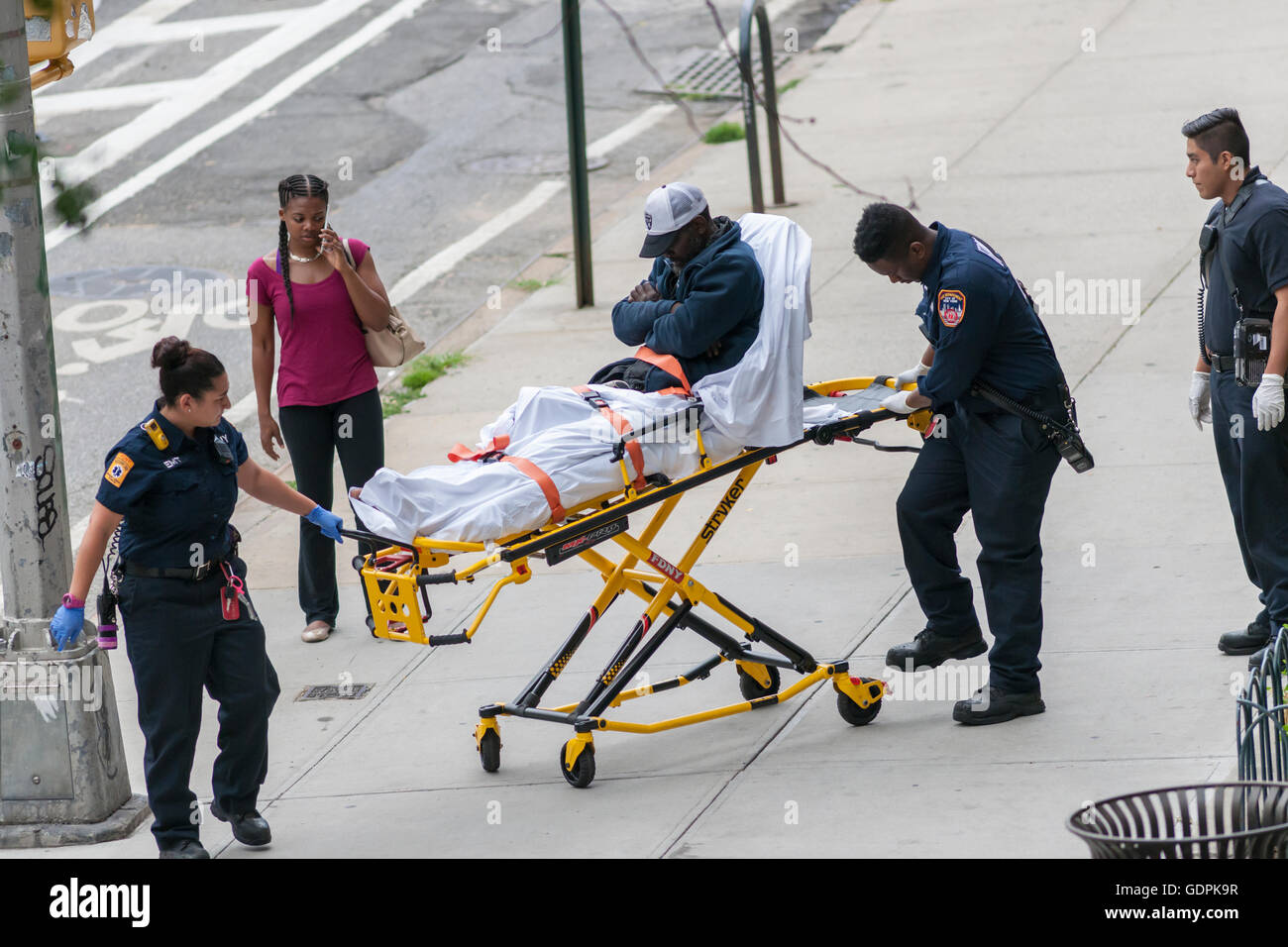 FDNY Emergency Service Technicians assist a homeless individual sleeping on the sidewalk in the Chelsea neighborhood of New York on Wednesday, July 3, 2016. (© Richard B. Levine) Stock Photo