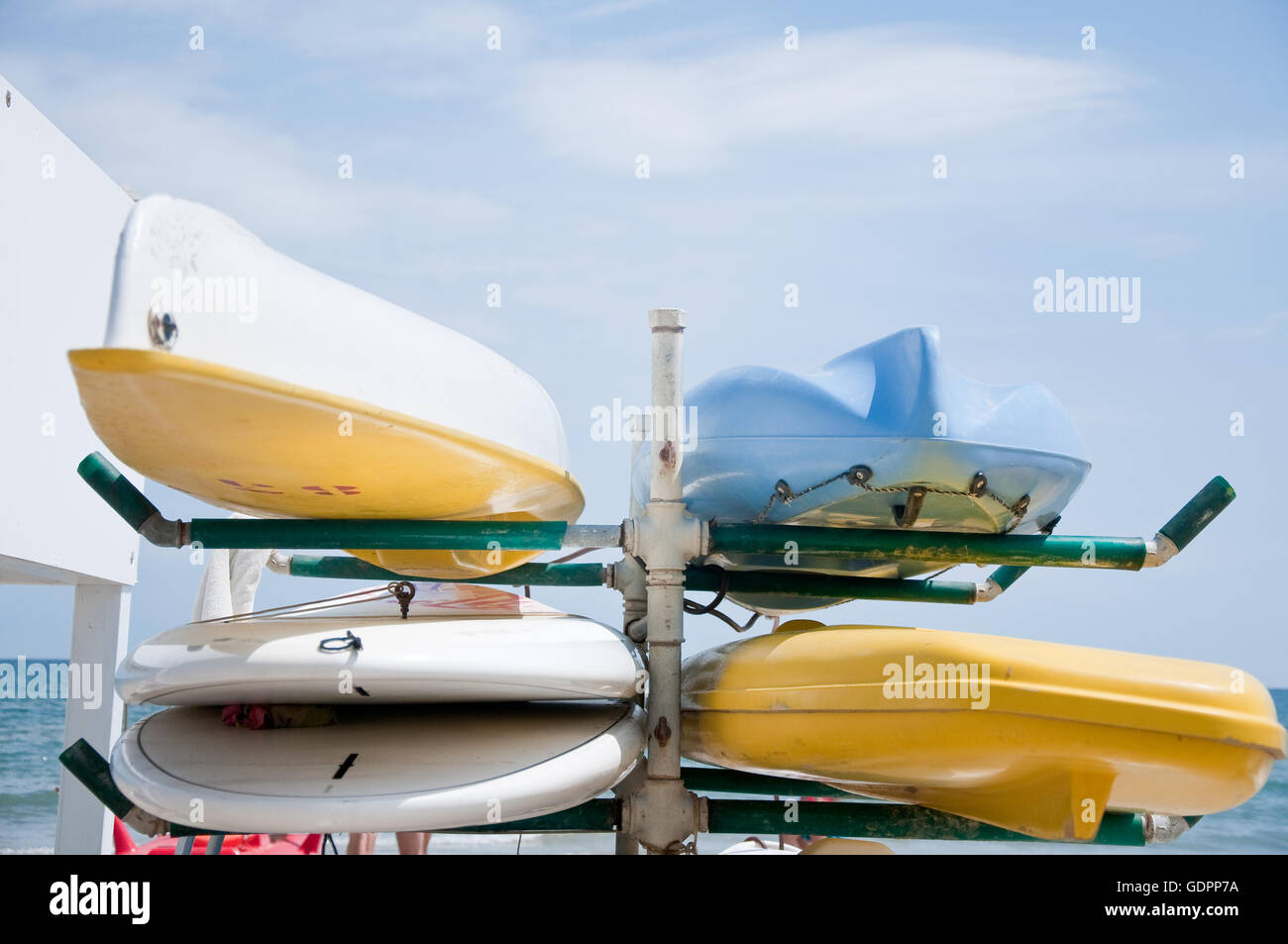 canoes of various colors lay in the sand Stock Photo