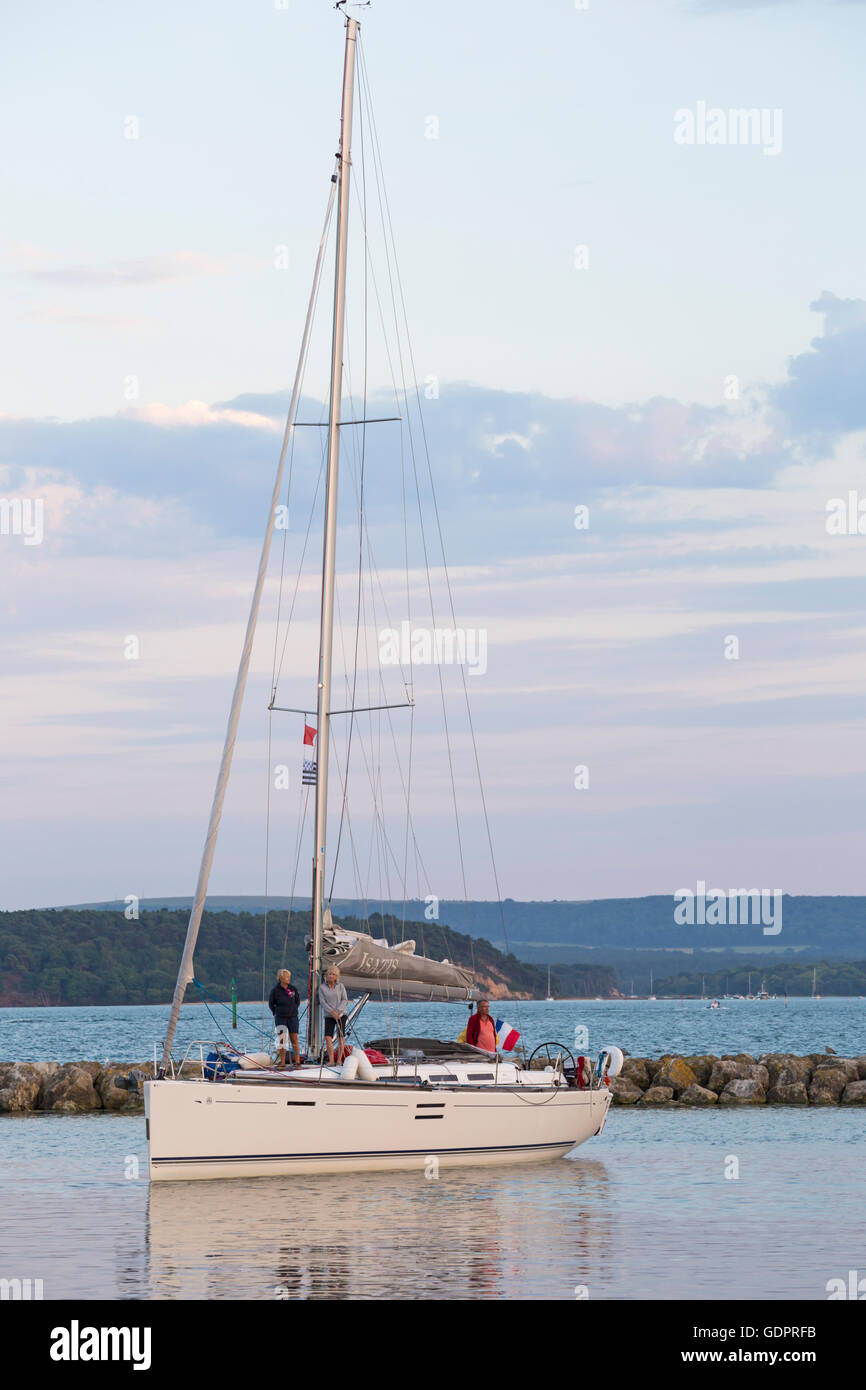 Yacht Isatis approaching Poole Marina after sailing in the evening light at Poole, Dorset in July Stock Photo