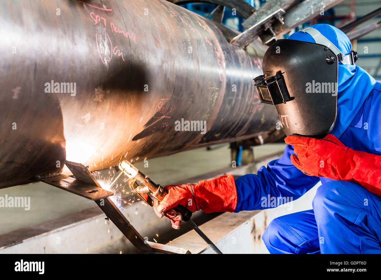 Welder in factory welding metal pipes Stock Photo