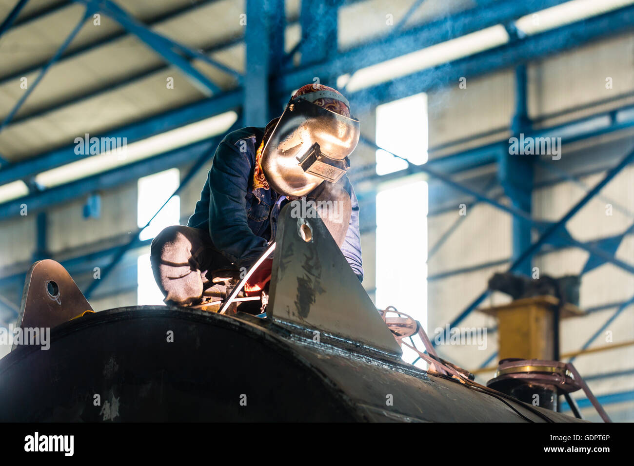 Welder working in an industrial setting manufacturing steel equipment