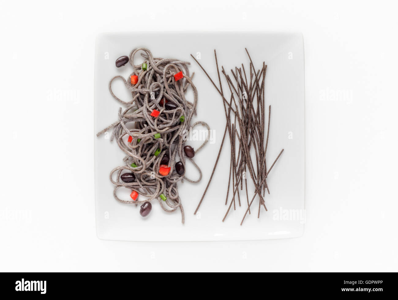 Cooked and raw organic Black Bean Spaghetti garnished with red Peppers and Chives Stock Photo