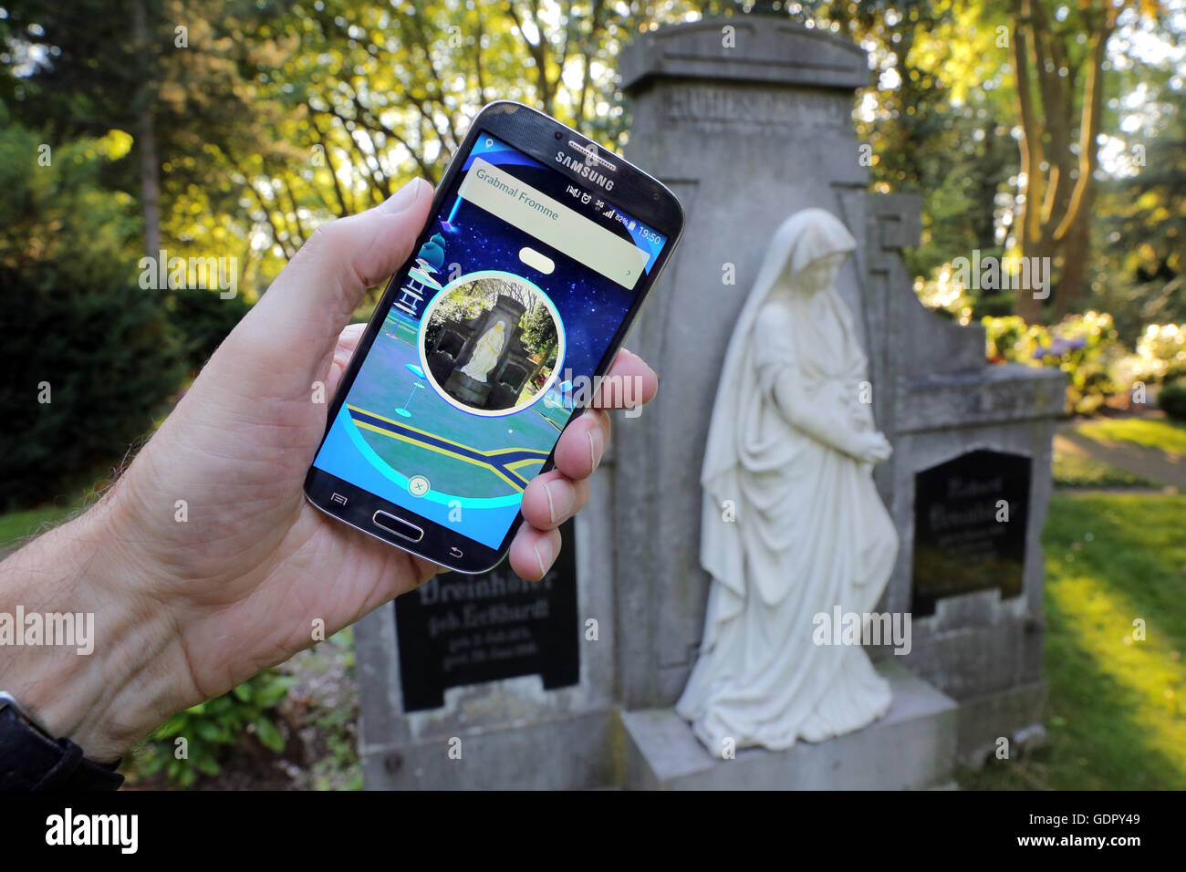 Pokémon go-player with his cellphone on a cemetery in Dortmund, Germany Stock Photo