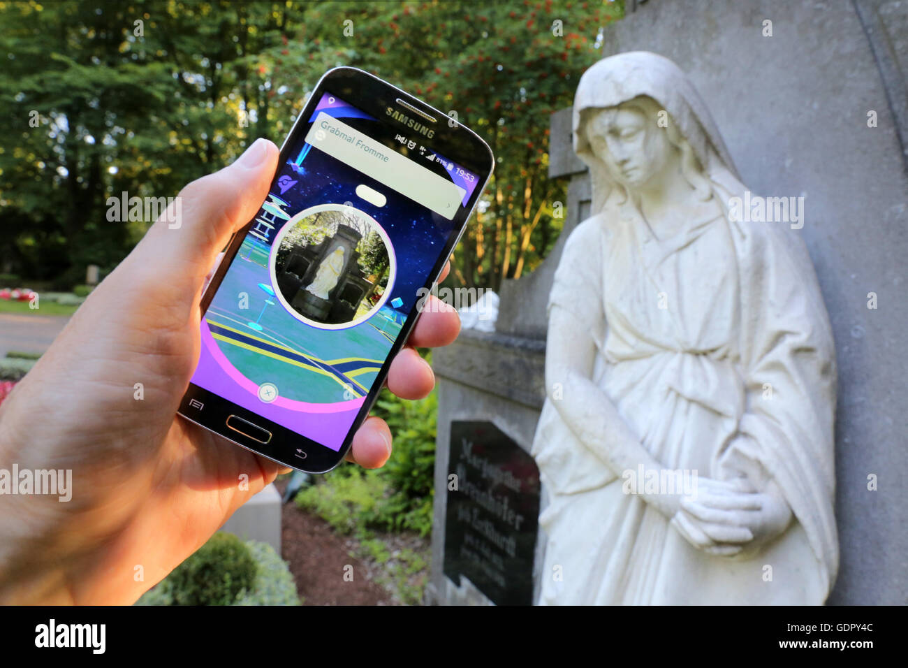 Pokémon go-player with his cellphone on a cemetery in Dortmund, Germany Stock Photo