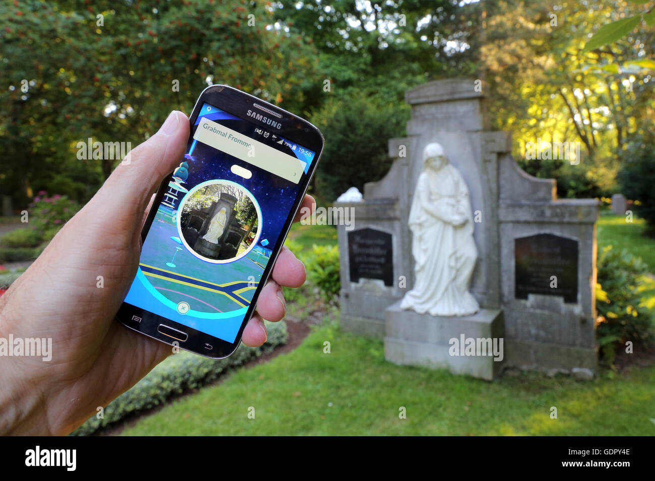 Pokémon go-player with his cellphone on a cemetery in Dortmund, Germany Stock Photo