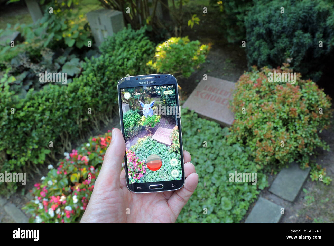 Pokémon go-player with his cellphone on a cemetery in Dortmund, Germany Stock Photo