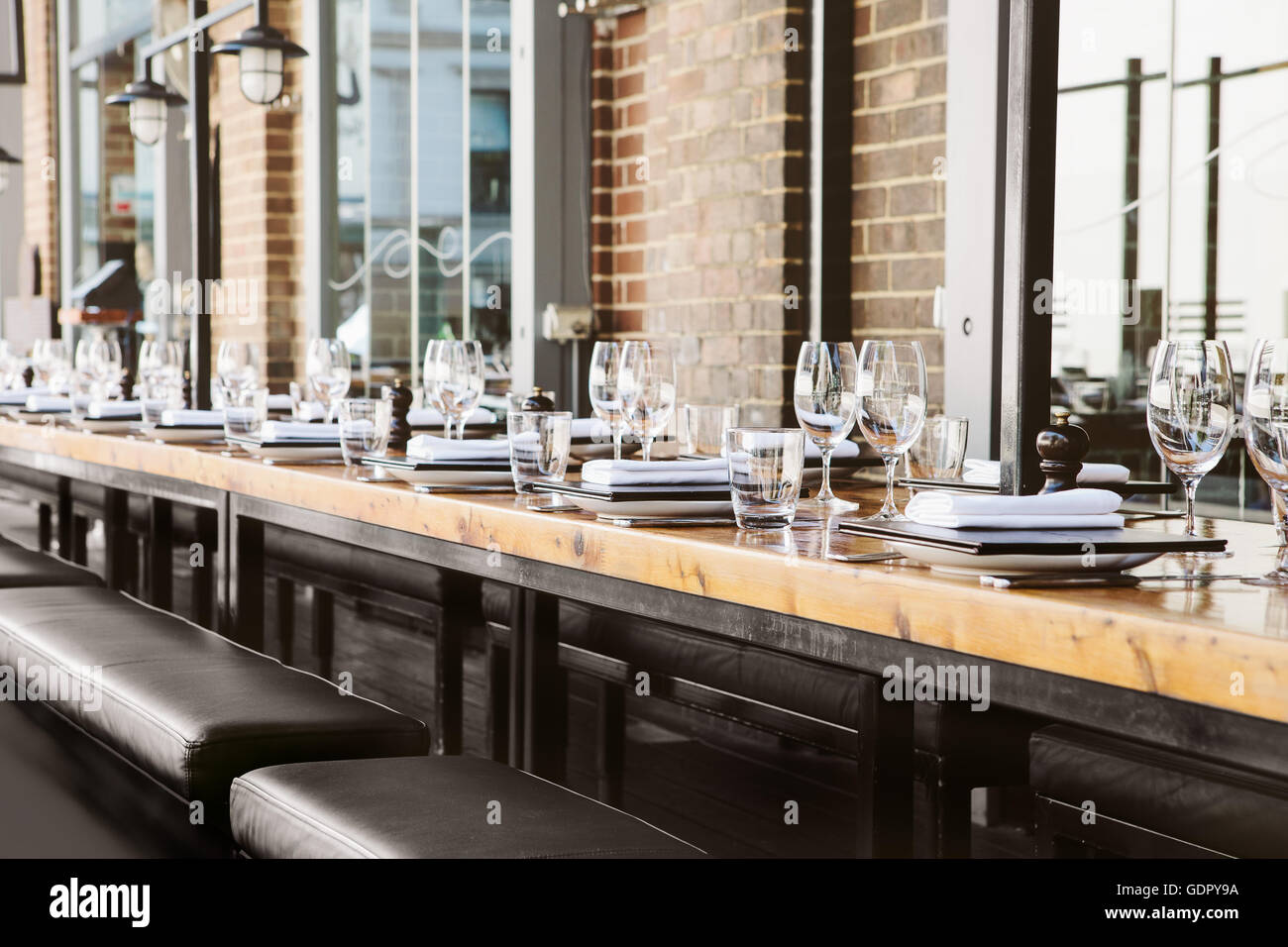 Empty glasses set in restaurant with long table Stock Photo - Alamy