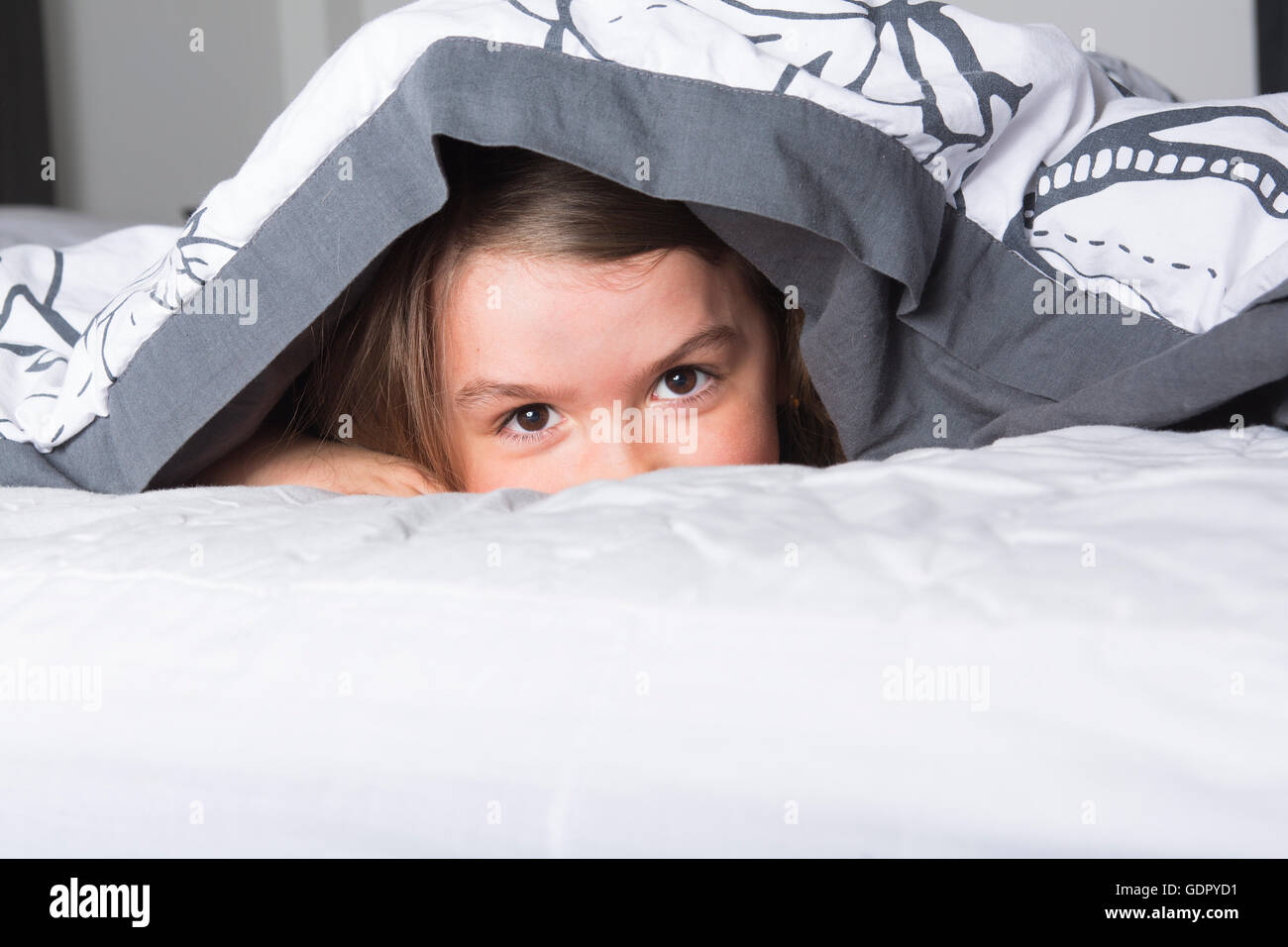 Child or teen under covers in bed Stock Photo