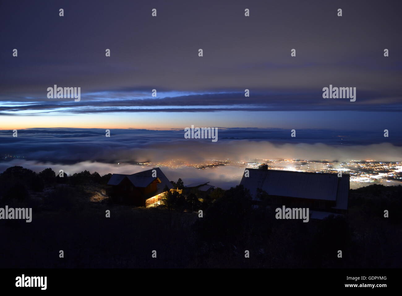 Winter evening with clouds settling down upon the city below.  Cabins that overlook the city. Stock Photo