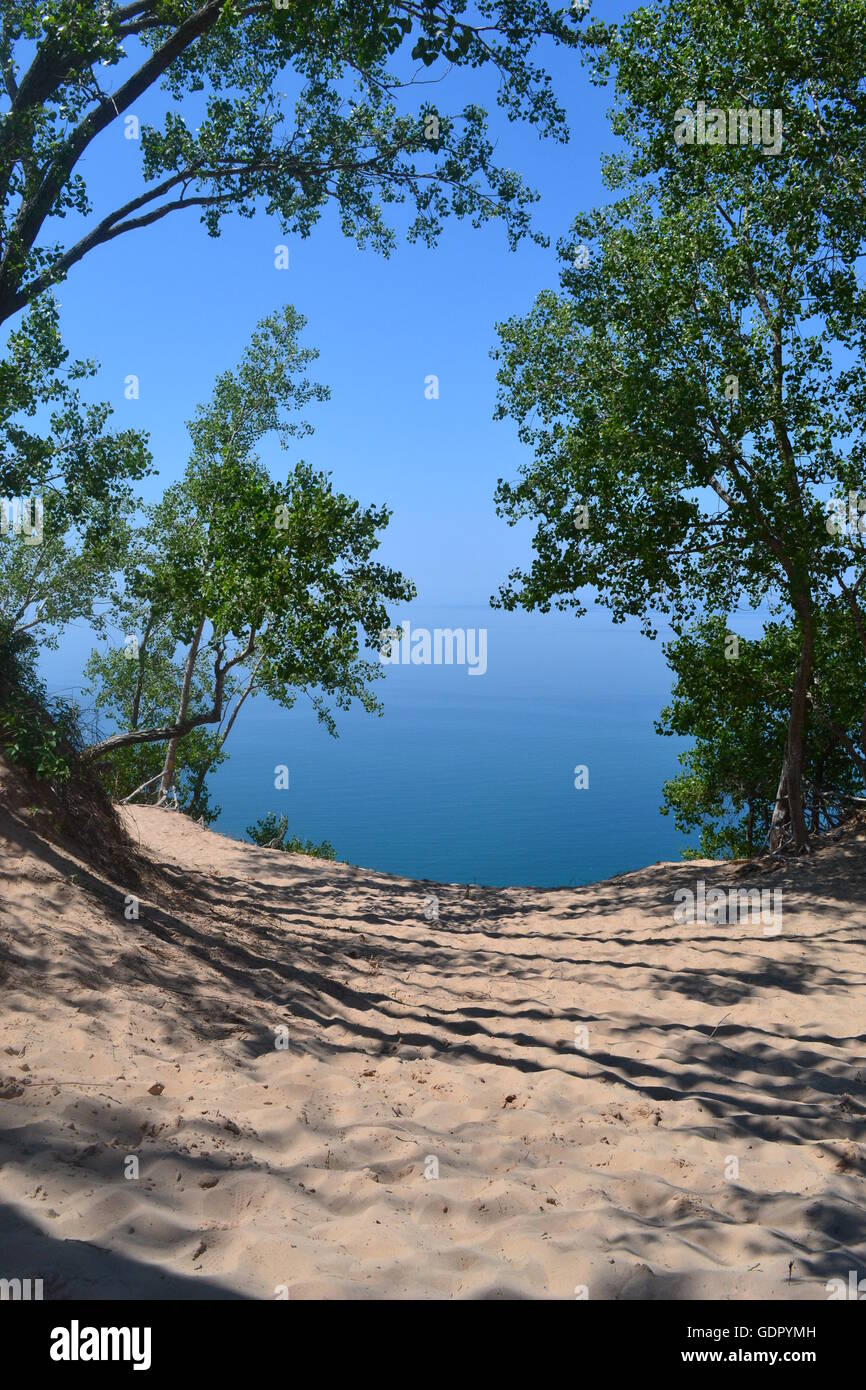 Sandy pathway surrounded by trees to the blue Colored Lake Michigan. Stock Photo