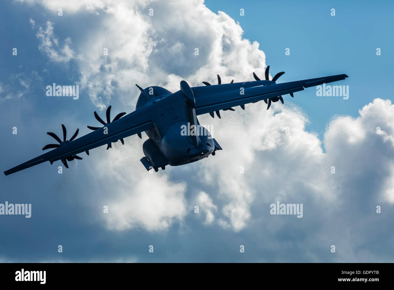A400M plane taking off and heading towards the sun. Contrejour image against dramatic cloud. Stock Photo