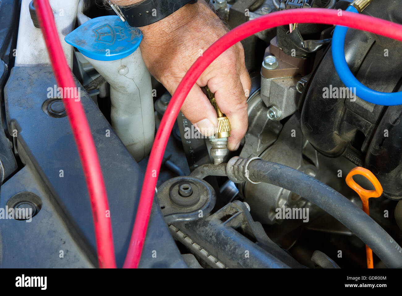 An automobile mechanic doing routine maintenance on an automobile air conditioning system. Stock Photo