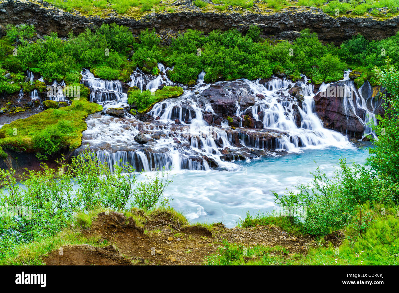 Hraunfossar Waterfalls a very beautiful waterfalls in west of Iceland. The clear water seeping through the lava and cascading do Stock Photo