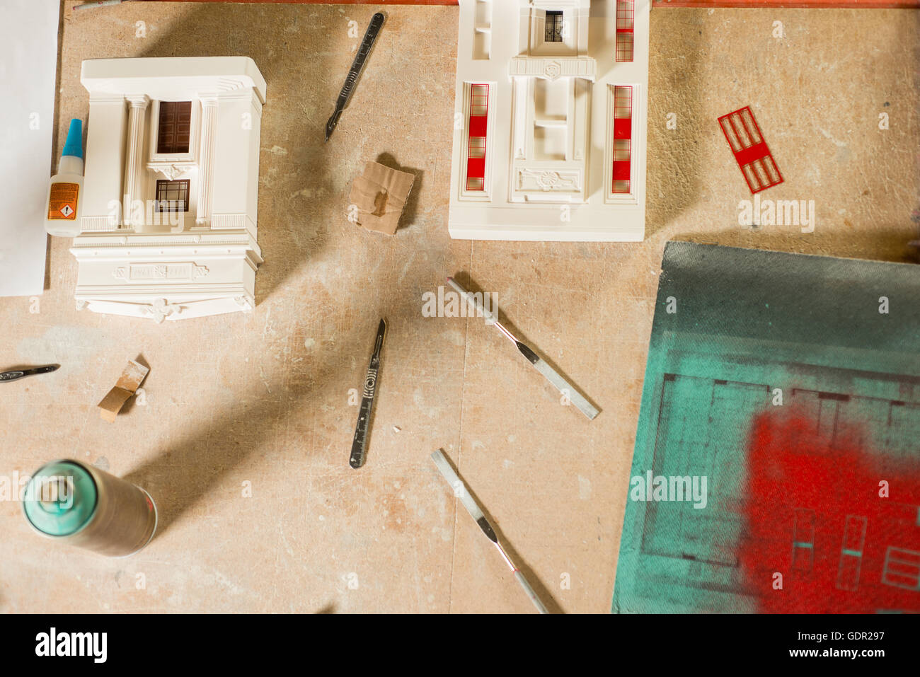 A couple of plaster scale model architectural buildings and their parts, tools, and materials including blades, files, glue, and Stock Photo