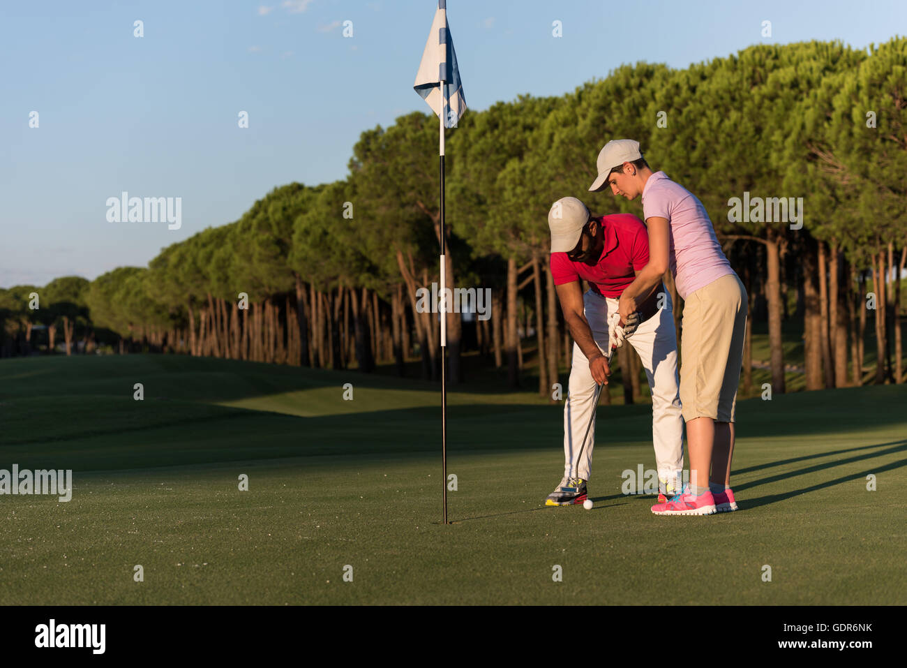 male golf instructor teaching female golf player, personal trainer