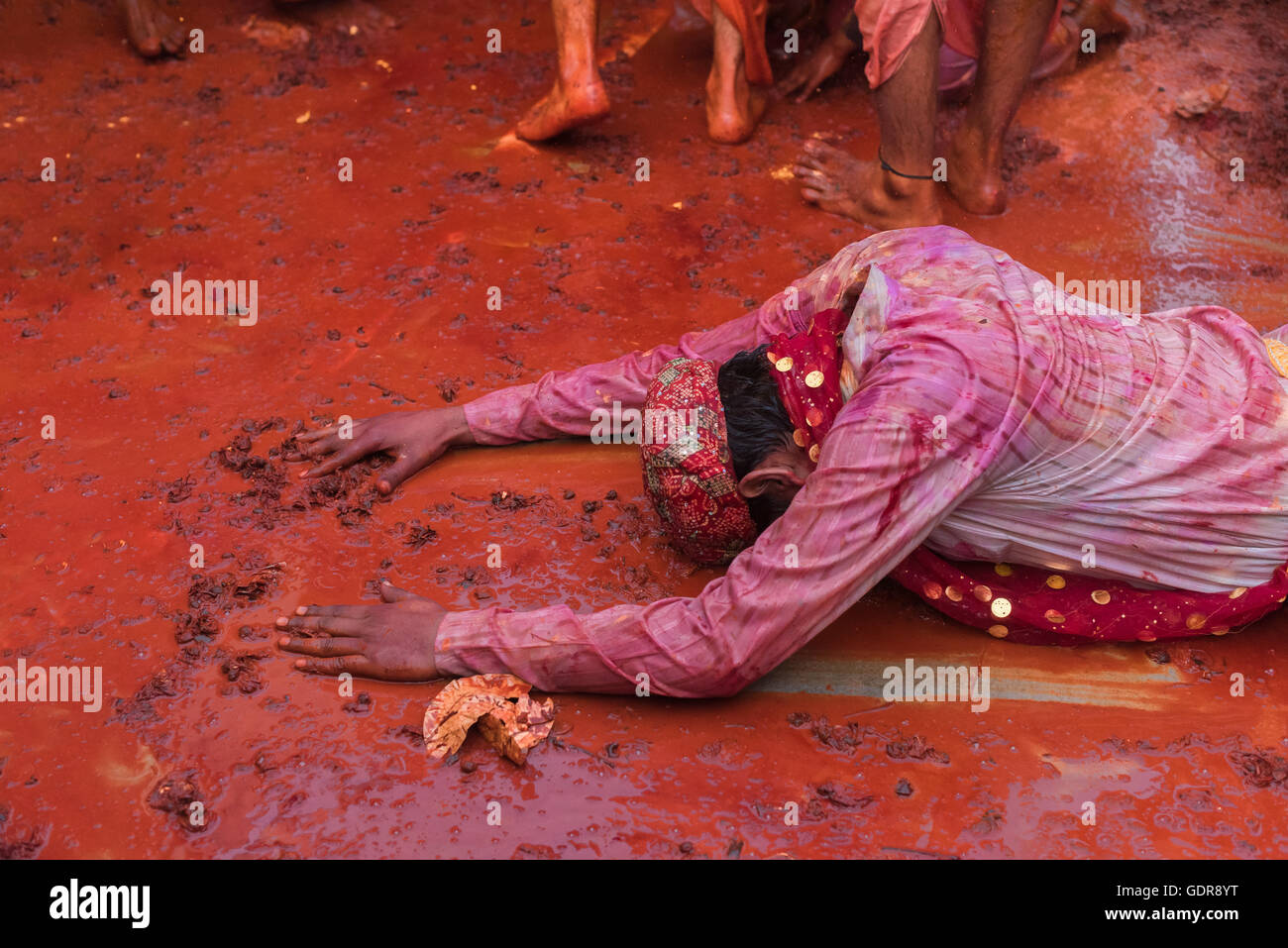 Nandgaon, India - March 10, 2014: Young male collecting flowers from ground and praying during holi celebration at temple. Stock Photo