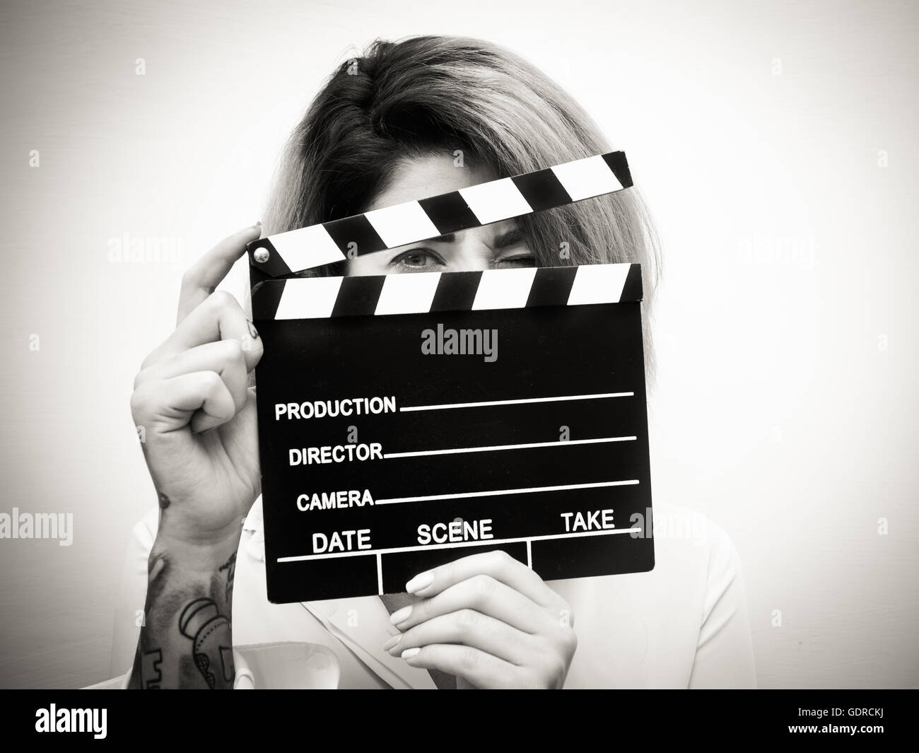 Young blonde woman actress close up with movie clapper behind face black and white Stock Photo
