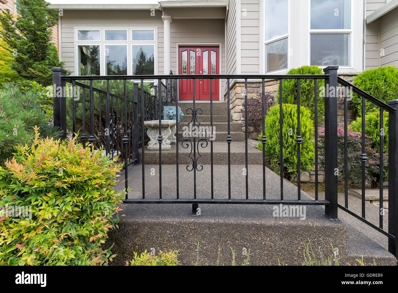 House front entrance with wrought iron railings on stairs with plants landscaping Stock Photo