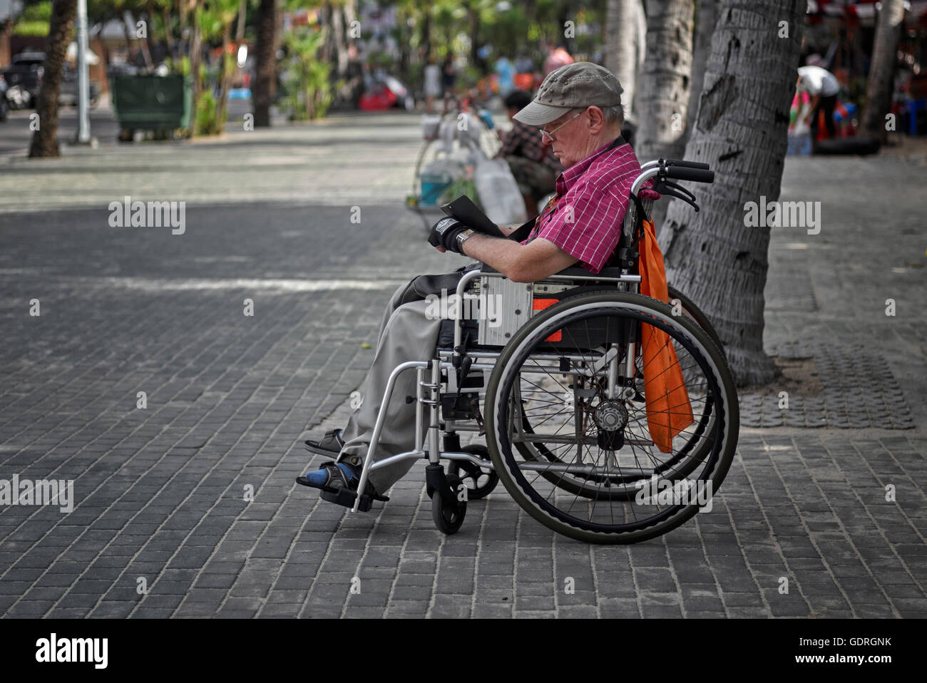 Disabled man in a wheelchair using a notebook story reader. Pattaya Thailand S. E. Asia Stock Photo