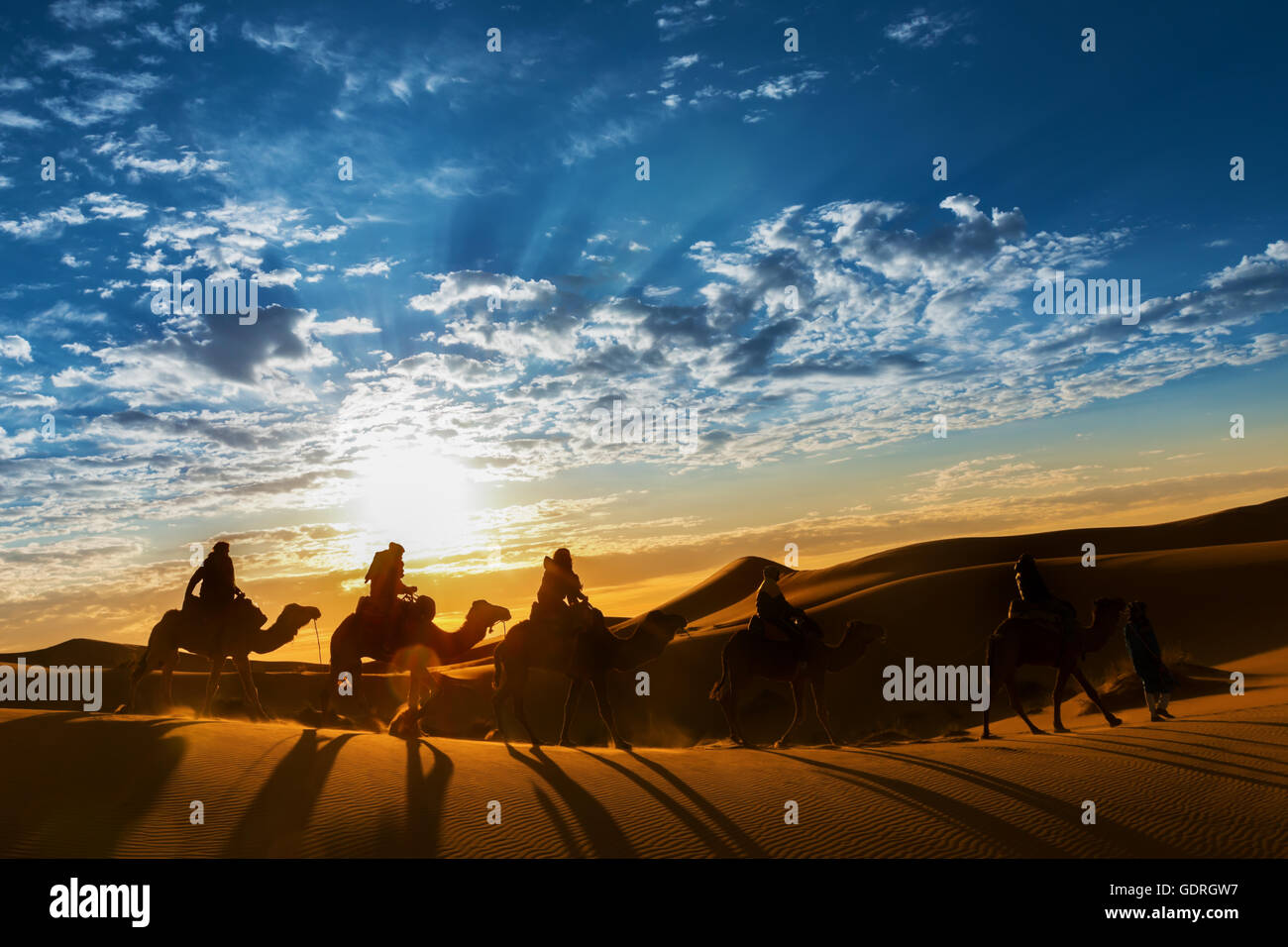 Caravan in the desert during sunrise against a beautiful cloudy sky, Erg Chebbi, Merzouga, Morocco. Stock Photo