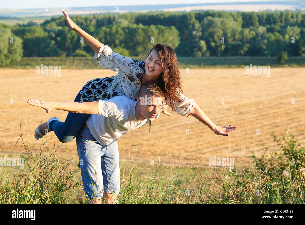 happy couple having fun on outdoor, girl riding on man back and fly ...