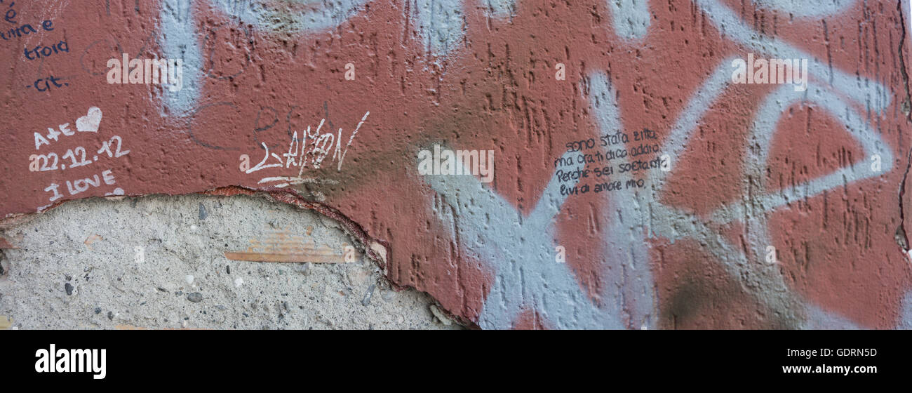 Graffiti,sprayed on a stone, Brick, wall, with Italian letters, on the brickwork with, white text shaded out, cracking, cladding Stock Photo