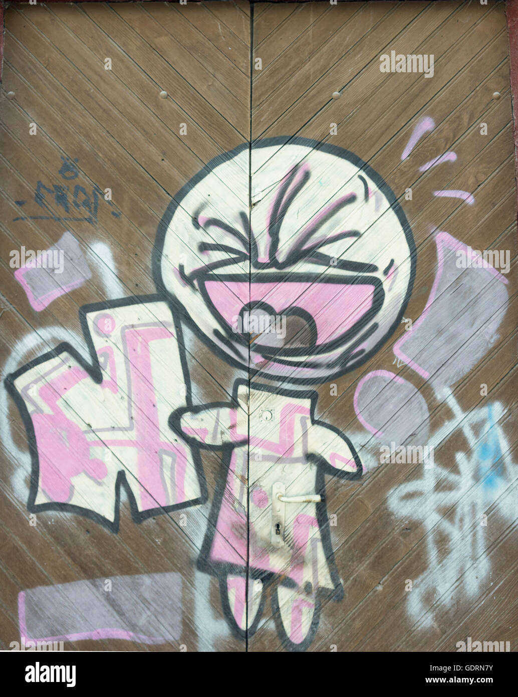 A powerful simple graffiti artwork, known as 'Bambin' which, is sprayed over a, cladded wall, and a large wooden, door. Stock Photo